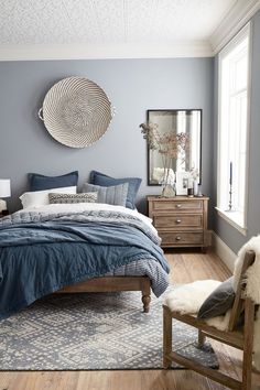 a bed room with a neatly made bed and a mirror on the wall above it