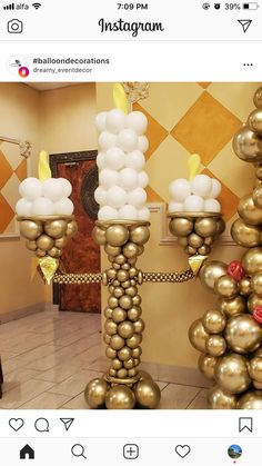 a bunch of balloons that are in the middle of a room with gold and white decorations