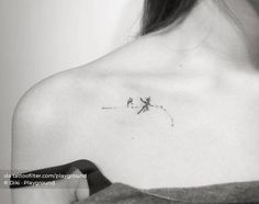 a black and white photo of a woman's shoulder with a small tattoo on it