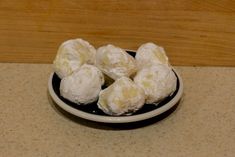 a black and white bowl filled with powdered sugar covered donuts on top of a counter