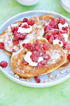 pancakes with raspberries and cream are on a plate next to bowls of oatmeal