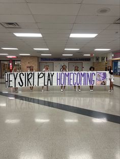 there is a sign that says hey sri play home coming with some girls in the background