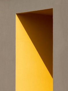 an open yellow door with the light coming in from it's center and shadow on the wall