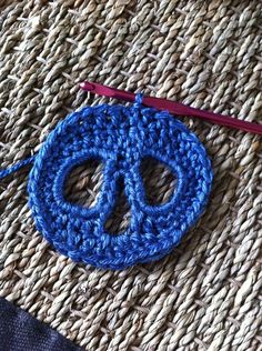 a blue crocheted peace sign sitting on top of a woven piece of cloth