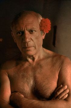 an old man with no shirt and flower in his hair is posing for the camera