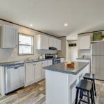 a large kitchen with white cabinets and stainless steel appliances, along with an island in the middle