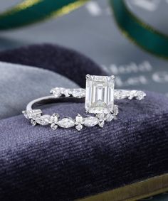 an emerald cut diamond ring on top of a velvet cushion