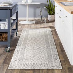 a kitchen with white cabinets and wood flooring next to a counter top on wheels