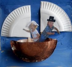 two children are in a boat made out of paper plates on a blue wall with white trim