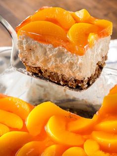 a piece of cheesecake with oranges on it being held by a metal spoon