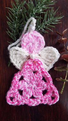 crocheted angel ornament next to pine branch on wooden table with needles