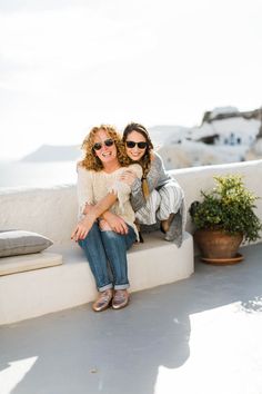 two women are sitting on a white bench