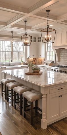 a large kitchen island with stools in front of it and lights hanging from the ceiling