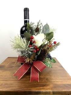 a bottle of wine sitting on top of a wooden table next to a christmas decoration