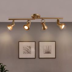 three lights are hanging from the ceiling in a room with two pictures on the wall