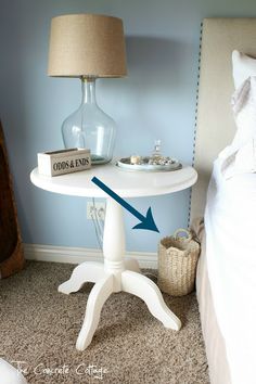 a white table with an arrow pointing to the end and a book on it next to a lamp