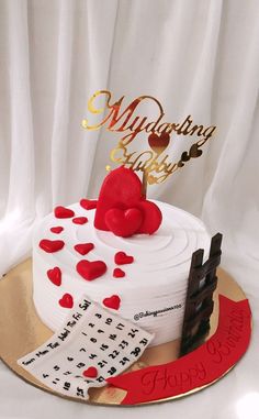 a white cake with red hearts on top sitting on a gold plated platter