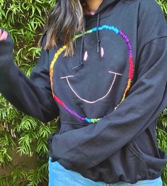 a woman wearing a black hoodie with a smiley face drawn on it