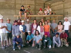 a group of people posing for a photo in front of a building with construction materials