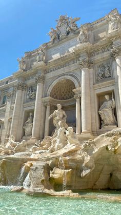 an ornate building with statues and fountains in front