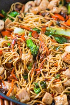 stir fry with chicken, broccoli, carrots and noodles in a skillet