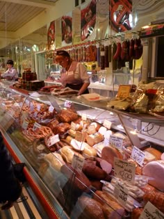 a display case filled with lots of different types of meats and cheeses in a store