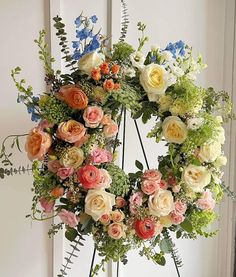 an arrangement of flowers arranged in a wreath on a stand next to a door with a window behind it