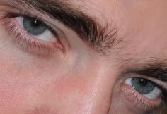 a close up of a person's eye with blue eyes and brown hair on his face