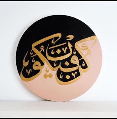 an arabic calligraphy on a black and pink circle with gold foil in the middle