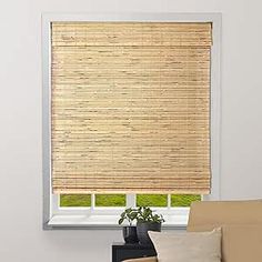 a living room with a couch and window covered in bamboo blinds