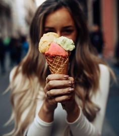 a woman is holding an ice cream cone in her hands