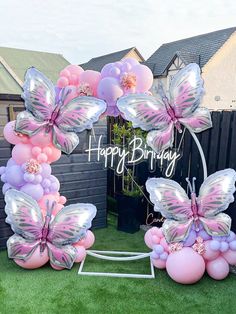 a bunch of balloons that are in the grass with some butterflies on top of them