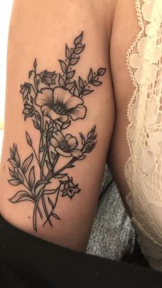 a woman's arm with flowers and leaves tattooed on the back of her shoulder