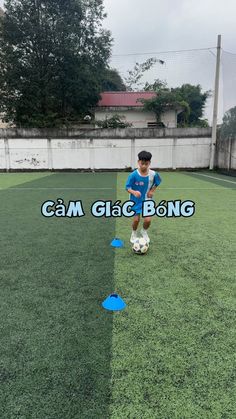 a young boy standing on top of a lush green field next to a soccer ball