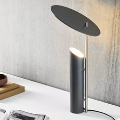 a lamp that is sitting on top of a table next to a book and magazine