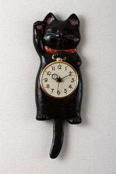 a black cat clock on the wall with it's hands up and eyes closed