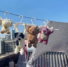 several stuffed animals hanging from clothesline with buildings in the background