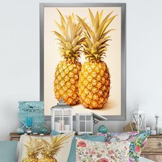 two pineapples sitting on top of each other in front of pillows and pictures