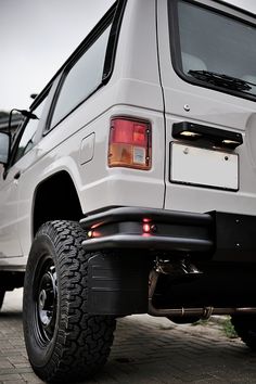 a white jeep parked on top of a brick road