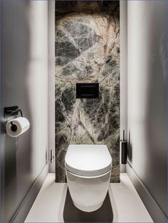 a white toilet sitting inside of a bathroom next to a roll of toilet paper on a towel dispenser