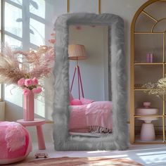 a mirror that is sitting in the middle of a room next to a pink chair