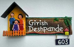 a wooden sign that says,'grish deshbande'and two people standing in front of a house