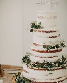 a three tiered wedding cake with greenery on top