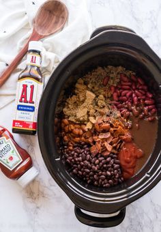 a crock pot filled with beans, meat and spices