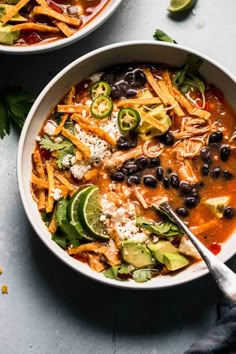 two bowls of mexican chicken tortilla soup with black beans, avocado and cilantro