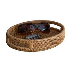 a wicker tray with sunglasses and cell phone on it, isolated against a white background