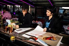 two people sitting at a table with papers