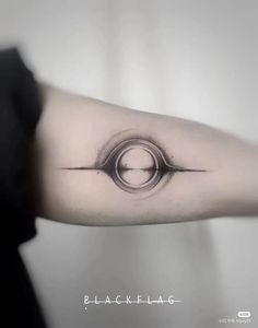 a black and white photo of a person's arm with a circle tattoo on it