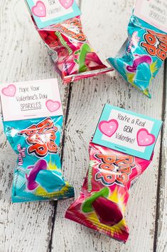 three bags of candy sitting on top of a white wooden table next to each other