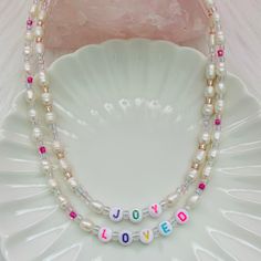 "Kawaii-ify your wardrobe with this super cute beaded pearl necklace. Each comes with freshwater pearls, premium iridescent Japanese Toho glass beads, and decorative plastic beads. This design is perfect for everyday wear and for layering with our other necklace designs. - Dimensions: 18\" necklace length with 2\" extender - Freshwater pearls with glass, clay, and plastic beads - Can be customized with your own name or saying. I'll reach out to you once you place your order to come up with a spe Trendy Pearl Necklace With Beaded Chain, Trendy Beaded Pearl Necklaces, Cute White Necklace With Letter Beads, Cute White Beaded Chain Necklace, Cute Pearl Jewelry With Colorful Beads, Cute Pearl Round Bead Necklaces, Cute White Beaded Necklaces With Letter Beads, Cute White Beaded Necklace With Letter Beads, Trendy Handmade Pearl Necklace